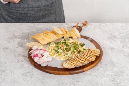 Téléchargez les photos : Assemblage d'une planche à beurre avec légumes et pain sur une planche à découper ronde en bois. - en image libre de droit