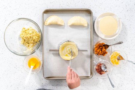 Photo for Flat lay. Filling empanada dough with egg filling to make breakfast empanadas with eggs and sweet potato. - Royalty Free Image