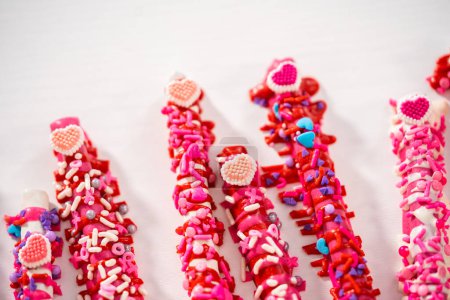 Foto de Barras de pretzel cubiertas de chocolate decoradas con chispas en forma de corazón para el Día de San Valentín. - Imagen libre de derechos