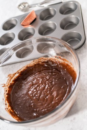Téléchargez les photos : Ramasser la pâte de cupcake dans les doublures de cupcake pour cuire des cupcakes aux fraises au chocolat. - en image libre de droit