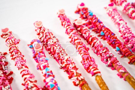 Téléchargez les photos : Baguettes de bretzel recouvertes de chocolat décorées de saupoudres en forme de cœur pour la Saint-Valentin. - en image libre de droit