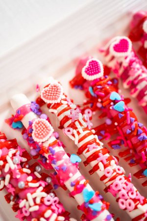 Téléchargez les photos : Baguettes de bretzel recouvertes de chocolat décorées de saupoudres en forme de cœur pour la Saint-Valentin. - en image libre de droit