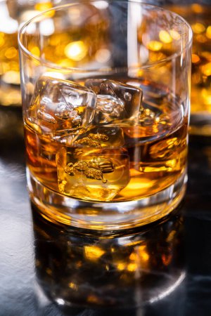 Photo for Scotch on the rocks in whiskey glass on a black marble surface. - Royalty Free Image