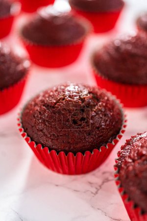 Foto de Enfriamiento recién horneado cupcakes de terciopelo rojo en un mostrador de cocina. - Imagen libre de derechos