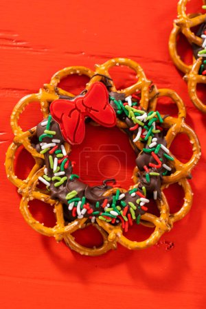 Photo for Chocolate pretzel Christmas wreath decorated with sprinkles and red chocolate bow on a red background. - Royalty Free Image
