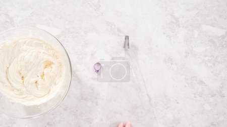 Téléchargez les photos : Pose plate. Pas à pas. Glaçage blanc crème au beurre dans un sac de tuyauterie avec une pointe en métal. - en image libre de droit