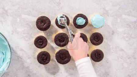 Photo for Flat lay. Step by step. Scooping blue buttercream frosting on top of the chocolate cupcakes. - Royalty Free Image