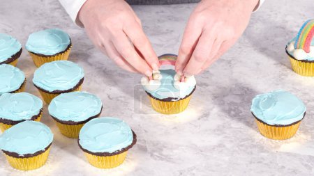 Foto de Paso a paso. Decoración de cupcakes de chocolate con glaseado de crema de mantequilla y dulces de arco iris. - Imagen libre de derechos