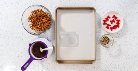 Téléchargez les photos : Flat lay. Dipping pretzels twists into melted chocolate to make a chocolate pretzel Christmas wreath. - en image libre de droit