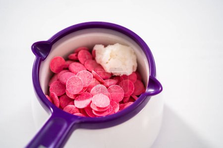 Téléchargez les photos : Fondre des pépites de chocolat dans un melting pot de bonbons pour faire des tiges de bretzel recouvertes de chocolat pour la Saint-Valentin. - en image libre de droit