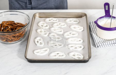 Foto de Sumergiendo pretzels tuerce en chocolate derretido para hacer giros de pretzel cubiertos de chocolate. - Imagen libre de derechos