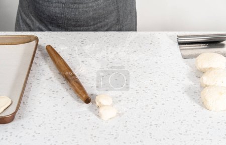 Photo for Rolling bread dough with a french rolling pin to bake naan dippers. - Royalty Free Image
