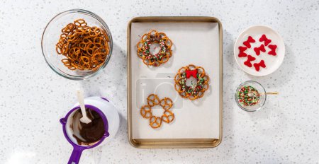 Foto de Flat lay. Dipping pretzels twists into melted chocolate to make a chocolate pretzel Christmas wreath. - Imagen libre de derechos