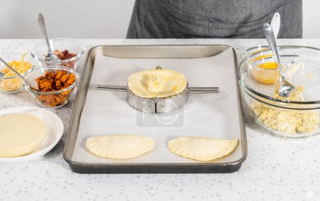 Téléchargez les photos : Remplir la pâte empanada avec du remplissage d'œufs pour faire des empanadas petit déjeuner avec des œufs et des patates douces. - en image libre de droit