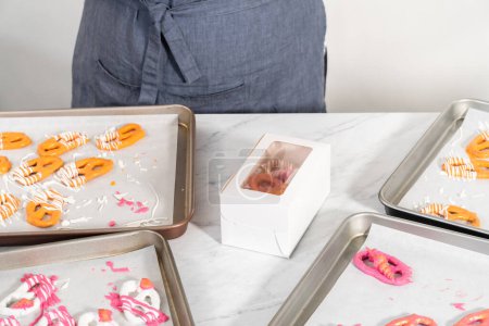 Foto de Embalaje gourmet chocolate cubierto torceduras pretzel en una caja de regalo de papel blanco lleno de trozos de papel. - Imagen libre de derechos