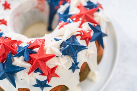 Photo for July 4th bundt cake covered with a vanilla glaze and decorated with chocolate stars on a white plate. - Royalty Free Image