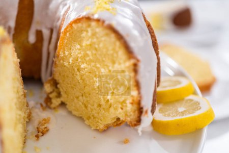 Téléchargez les photos : Gâteau de lapin au citron tranché décoré de zeste de citron sur un stand de gâteau. - en image libre de droit