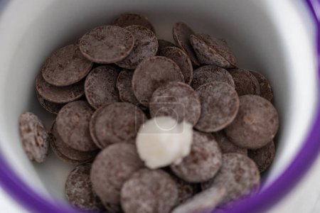 Foto de El chocolate derretido se derrite en un crisol de dulces para preparar mini chocolates gourmet con chispas. - Imagen libre de derechos