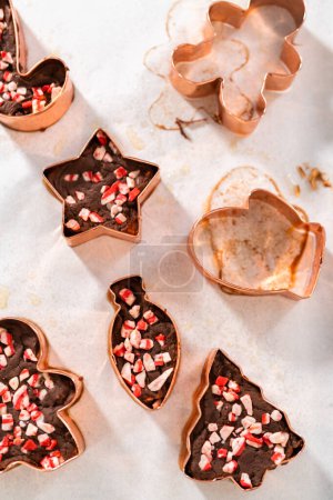 Removing freshly made Christmas cookie-cutter peppermint fudge from cookie cutters.