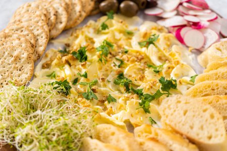 Téléchargez les photos : Planche à beurre avec légumes et pain sur une planche à découper ronde en bois. - en image libre de droit
