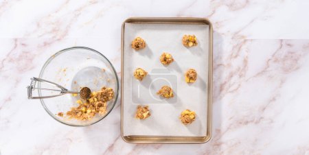 Téléchargez les photos : Pose plate. Enfoncer la pâte à biscuits dans la plaque à pâtisserie tapissée de papier parchemin pour faire cuire les biscuits à l'avoine de pomme. - en image libre de droit