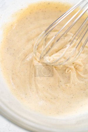 Téléchargez les photos : Mélanger les ingrédients dans un grand bol à mélanger en verre pour faire la vinaigrette pour la salade de macaronis avec du poulet. - en image libre de droit