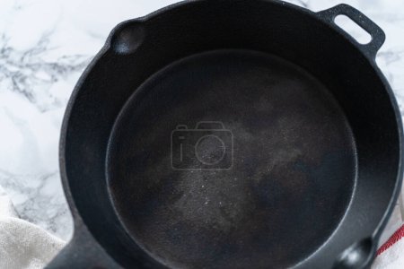 Foto de Calentar la sartén de hierro fundido sobre la estufa para preparar espinacas y jamón frittata. - Imagen libre de derechos