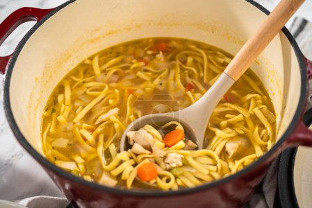 Téléchargez les photos : Servir de la soupe de nouilles de poulet avec des nouilles kluski dans des bols à soupe en céramique blanche. - en image libre de droit