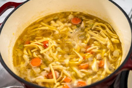 Photo for Cooking chicken noodle soup with kluski noodles in an enameled dutch oven. - Royalty Free Image