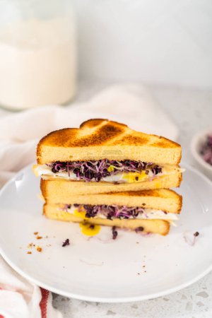 Foto de Huevo de desayuno en rodajas y sándwich de brote en un plato blanco. - Imagen libre de derechos
