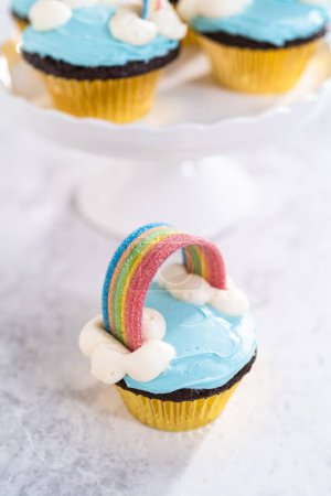 Photo for Chocolate cupcakes decorated with blue buttercream frosting and rainbow for unicorn theme birthday party. - Royalty Free Image