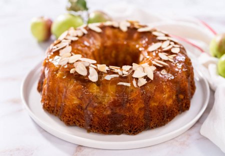 Photo for Freshly baked apple bundt cake with caramel glaze on a white plate. - Royalty Free Image