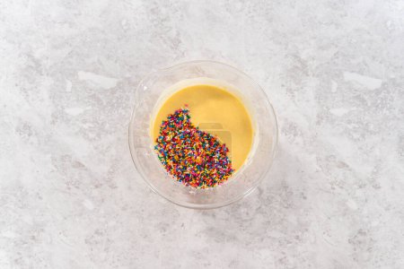 Photo for Flat lay. Mixing ingredients in a glass mixing bowl to bake funfettti bundt cake. - Royalty Free Image