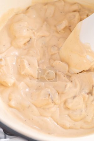 Photo for Mixing ingredients in an enameled dutch oven to prepare chicken alfredo pasta. - Royalty Free Image