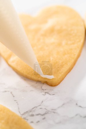 Décoration de biscuits au sucre en forme de c?ur avec glaçage royal rose et blanc pour la Saint-Valentin.