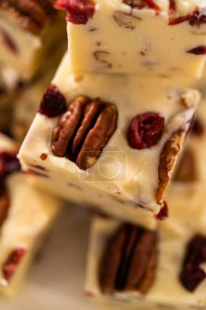 Photo for Homemade white chocolate cranberry pecan fudge pieces on a white ceramic plate. - Royalty Free Image