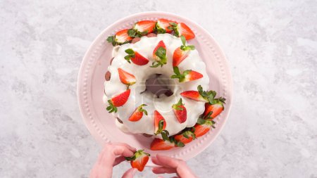 Photo for Flat lay. Step by step. Decorating freshly baked red velvet bundt cake with organic strawberries. - Royalty Free Image