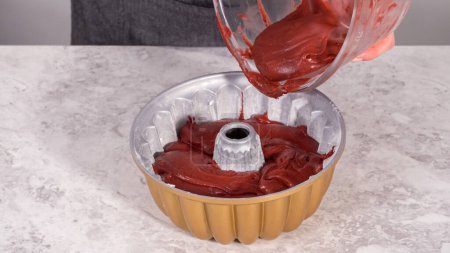 Photo for Step by step. Pouring cake batter into a bundt cake pan to bake a red velvet bundt cake. - Royalty Free Image
