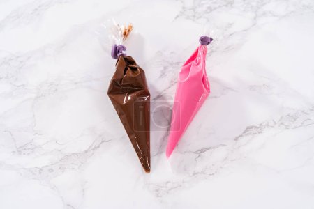 Photo for Melted chocolate in piping bags ready for drizzling over chocolate-covered strawberries. - Royalty Free Image