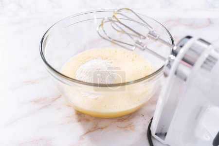 Foto de Mezclar los ingredientes en un tazón de vidrio grande para hornear magdalena sharlotka manzana. - Imagen libre de derechos