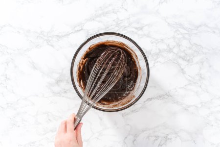 Photo for Flat lay. Mixing ingredients in a large glass mixing bowl to bake chocolate peppermint cupcakes. - Royalty Free Image