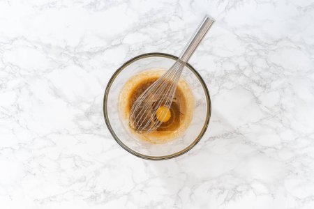 Téléchargez les photos : Pose plate. Mélanger les ingrédients humides dans un grand bol à mélanger en verre pour faire cuire des muffins de graines de pavot citron. - en image libre de droit