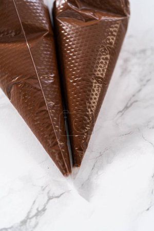 Téléchargez les photos : Chocolat fondu dans des sacs de tuyauterie préparés pour le glaçage biscuits sablés en forme de panda. - en image libre de droit