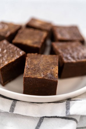 Téléchargez les photos : Pièces de caramel au beurre d'arachide au chocolat maison sur une plaque en céramique blanche. - en image libre de droit