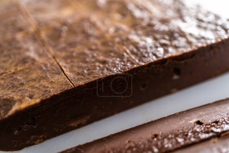 Foto de Cortar la mantequilla de cacahuete de chocolate en trozos pequeños en una tabla de cortar blanca. - Imagen libre de derechos