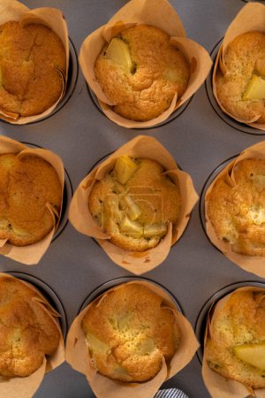 Téléchargez les photos : Refroidissement des muffins sharlotka aux pommes fraîchement cuits sur un comptoir de cuisine. - en image libre de droit