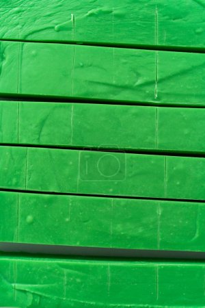 Foto de Corte de dulce verde con un cuchillo de cocina grande en piezas cuadradas en una tabla de cortar blanca. - Imagen libre de derechos