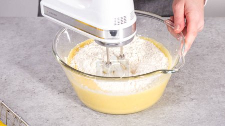Téléchargez les photos : Pas à pas. Mélanger les ingrédients dans un bol de mélange en verre pour préparer le gâteau bundt aux canneberges au citron. - en image libre de droit