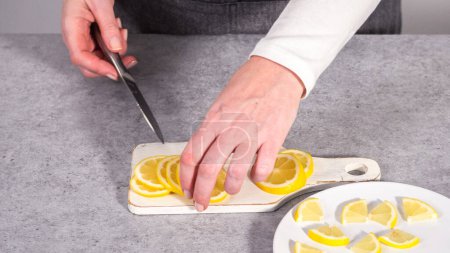 Foto de Paso a paso. Cortar rodajas de limón orgánico en un plato blanco. - Imagen libre de derechos