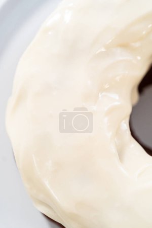 Foto de Verter esmalte de queso crema sobre pastel de terciopelo rojo recién horneado. - Imagen libre de derechos